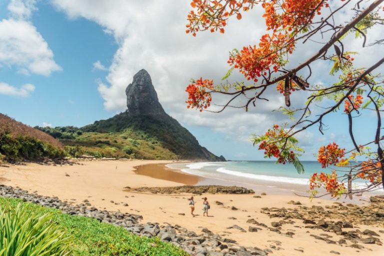 Fernando De Noronha - people on beach near rocky mountain under blue and white sunny cloudy sky during daytime