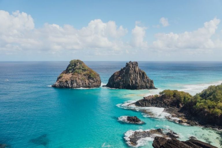 Fernando De Noronha - brown and green rock formation on blue sea under white clouds and blue sky during daytime