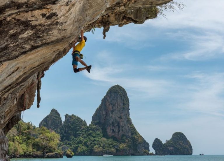 Rock Climbing - man climbing cliff beside beach