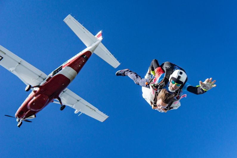 Skydiving - white and red airplane in mid air during daytime