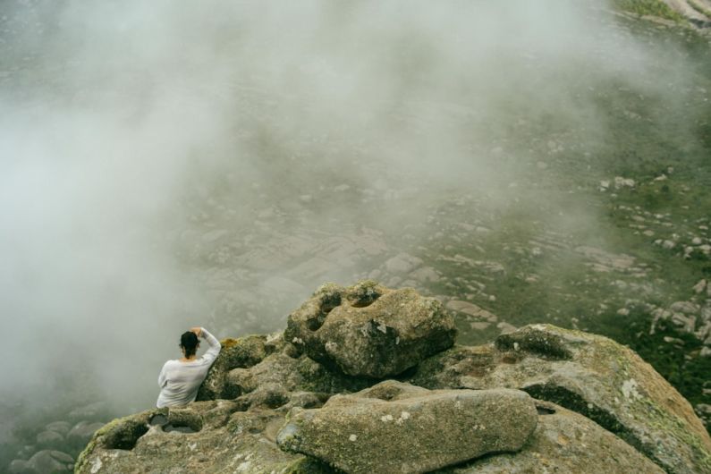 Itatiaia - aerial photography of man sitting on peak of rock formation