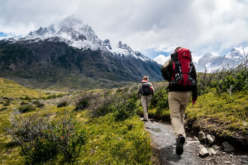 Trekking - two person walking towards mountain covered with snow