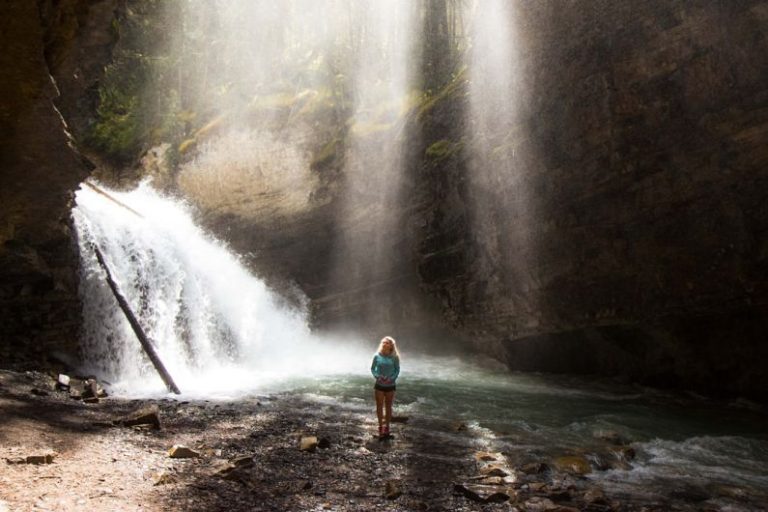 Waterfall Hiking - woman standing near river under gray sky during daytime